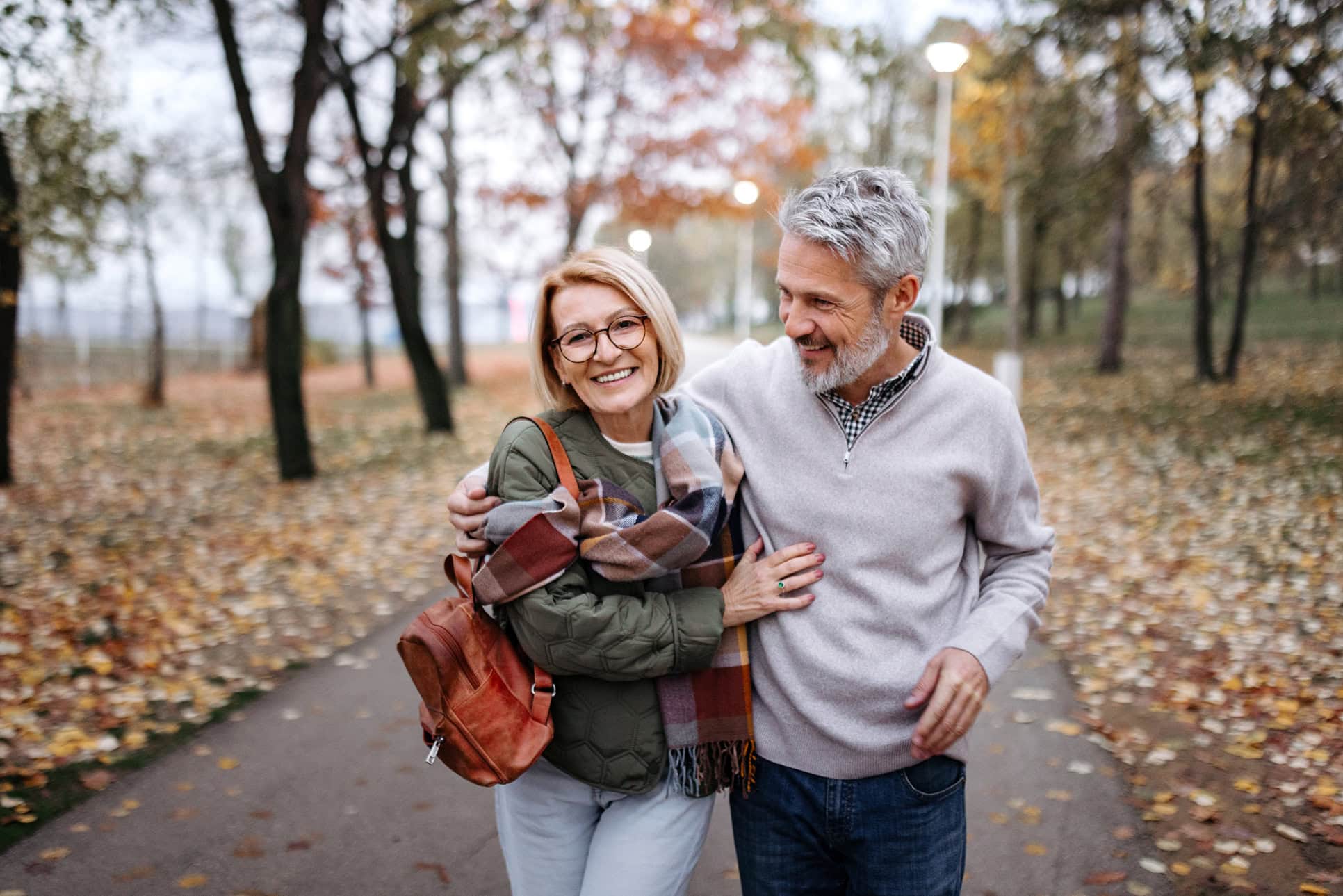 A mature couple walks together through a public park, enjoying time outdoors. Captures companionship, active lifestyle, and relaxed leisure moments.
