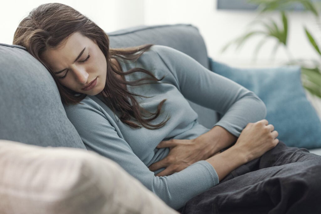 donna con dolore alla pancia sul divano